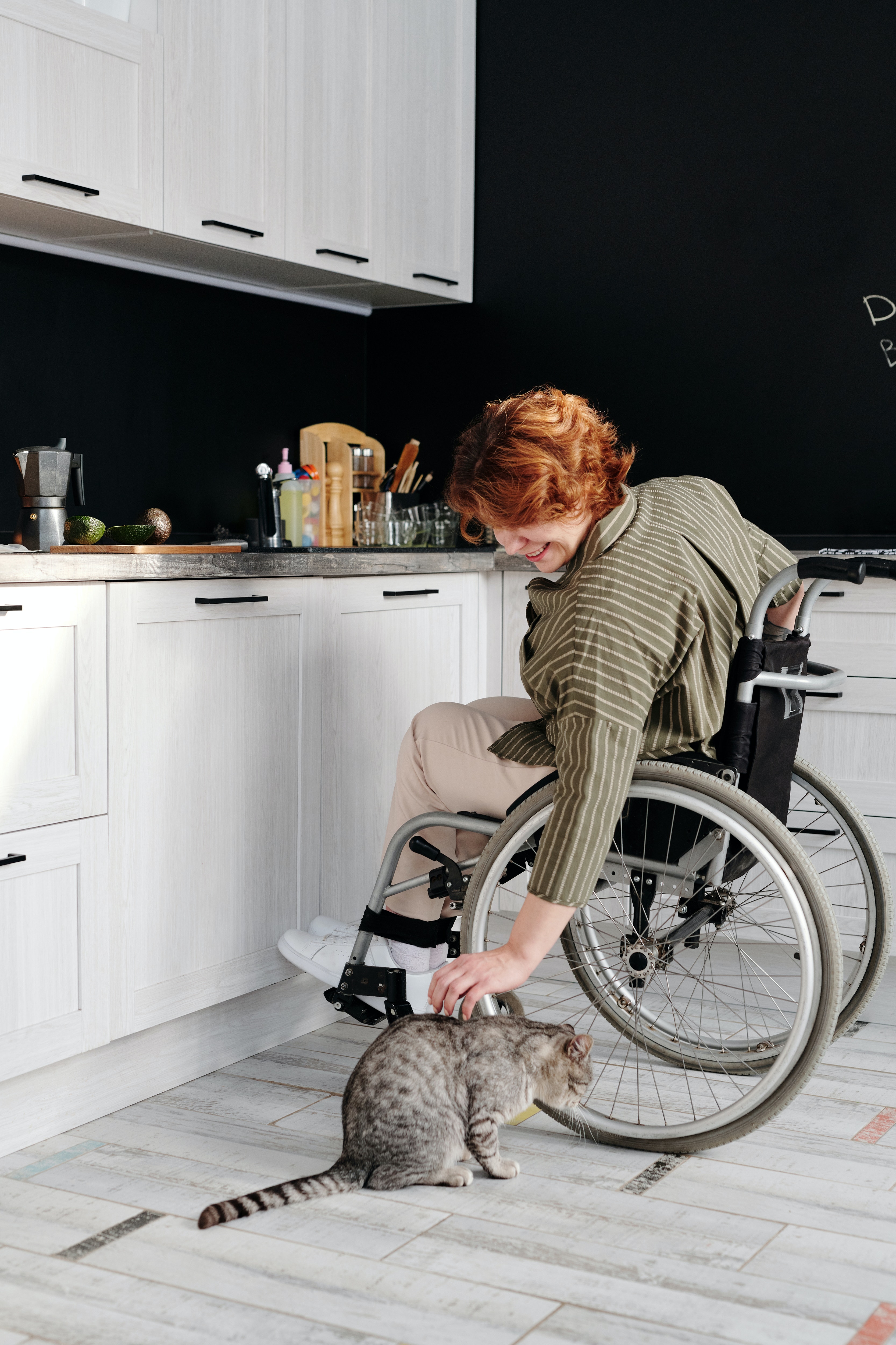 Woman in a Wheelchair Leaning Over and Petting Her Cat Woman in a Wheelchair Leaning Over and Petting Her Cat