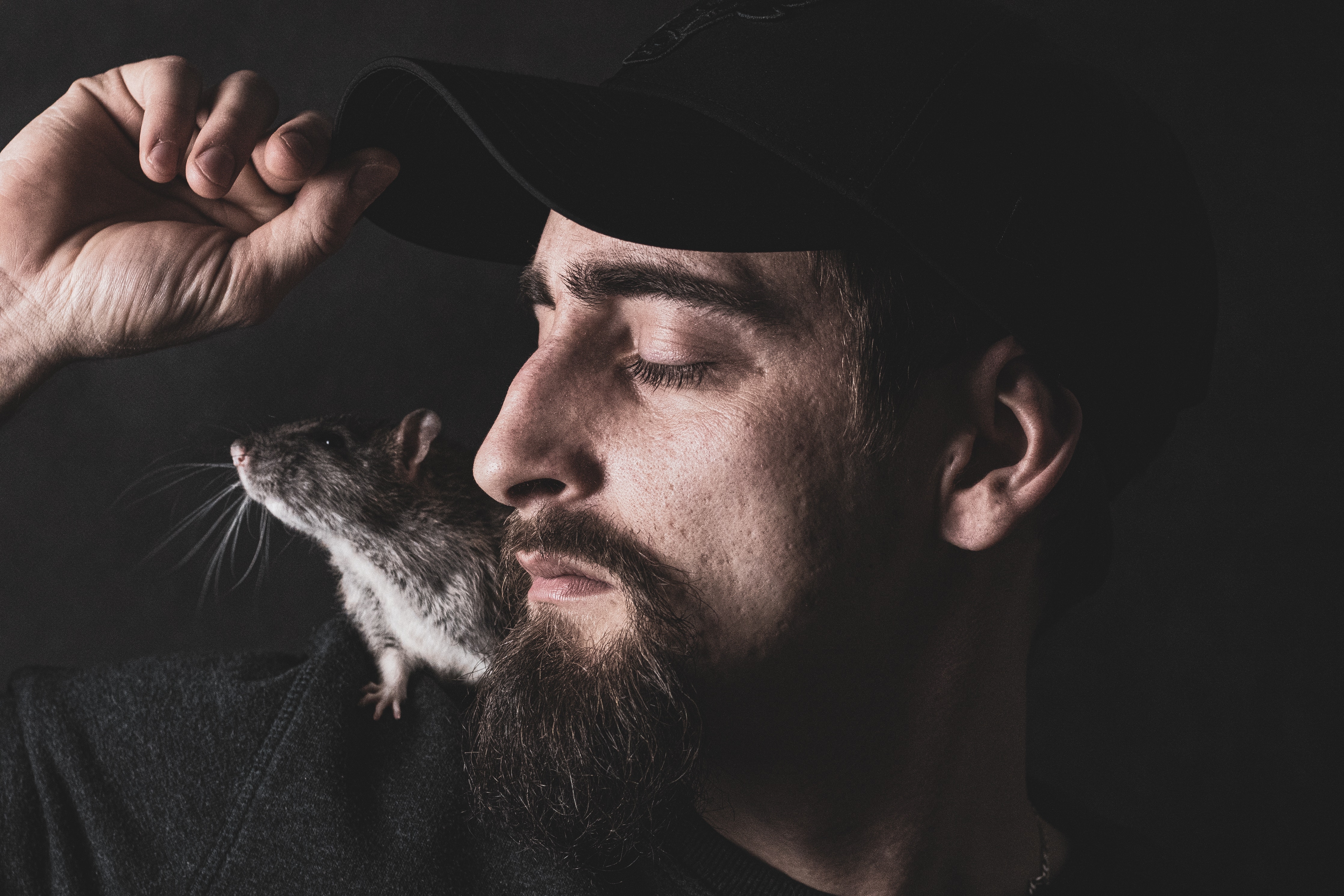 Man with a Rat on His Shoulder. It Looks Like He is Trying to Feed it or Pet It.