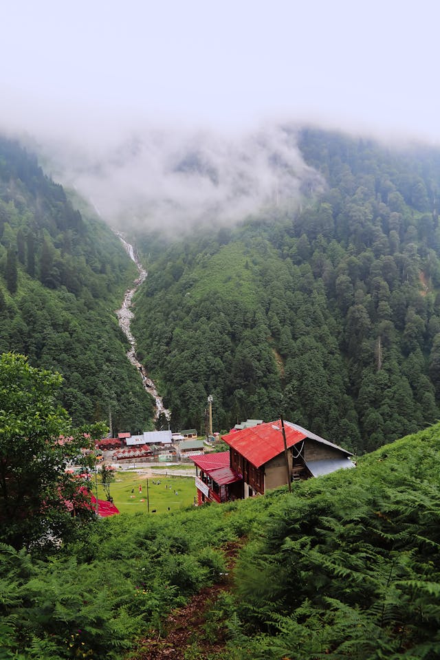 A Peaceful Valley With a Hotel at the Bottom and a Waterfall in the Background  A Peaceful Valley With a Hotel at the Bottom and a Waterfall in the Background