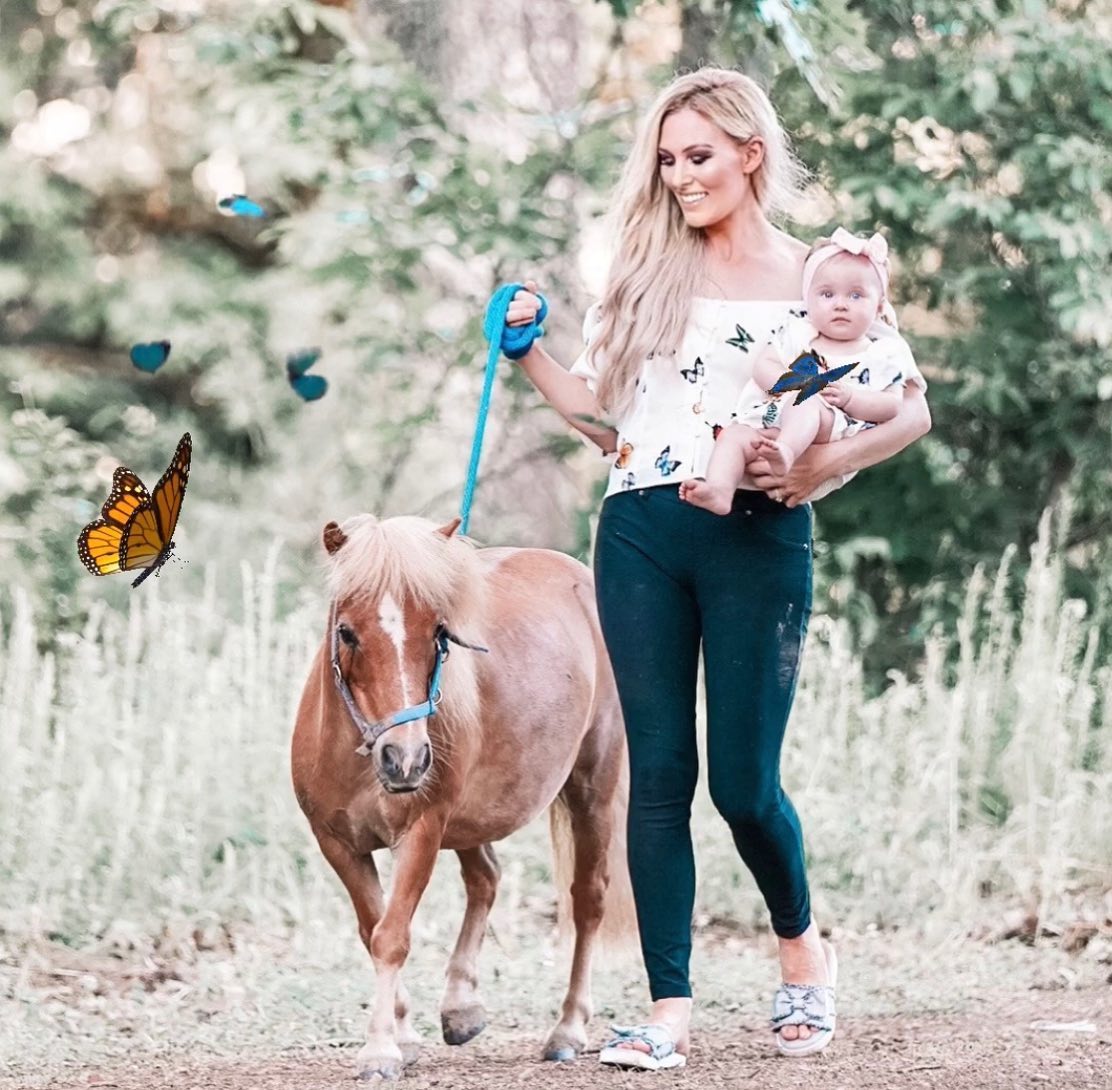 Stephanie Holding a Baby in her Left Hand and the Leash of a Donkey in her Right Hand.