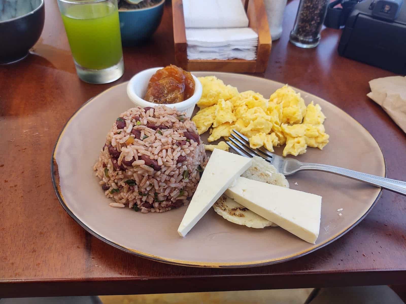 A Breakfast With Eggs, Cheese, Jam, Tortilla, and Rice and Beans